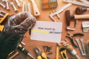 How Much do tradespeople get paid? A Man picks up a business card from a workbench